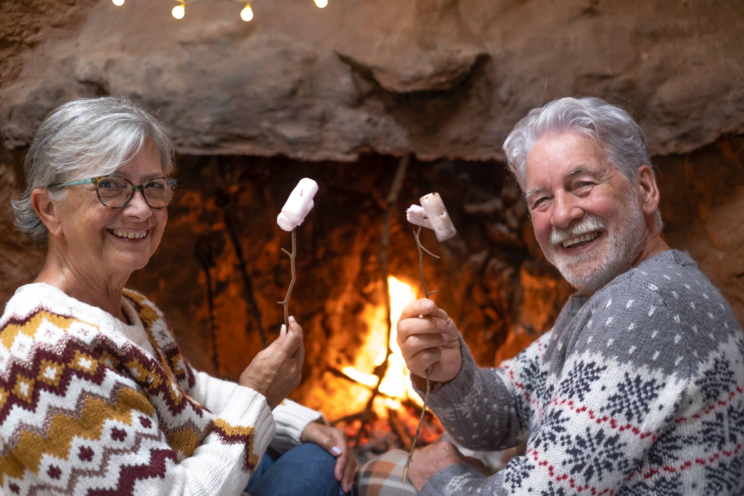 Happy senior couple in front of the fireplace while roasting mar